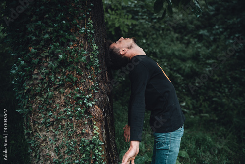 Young man leaning near a tree in the forest thinks © mahirkart