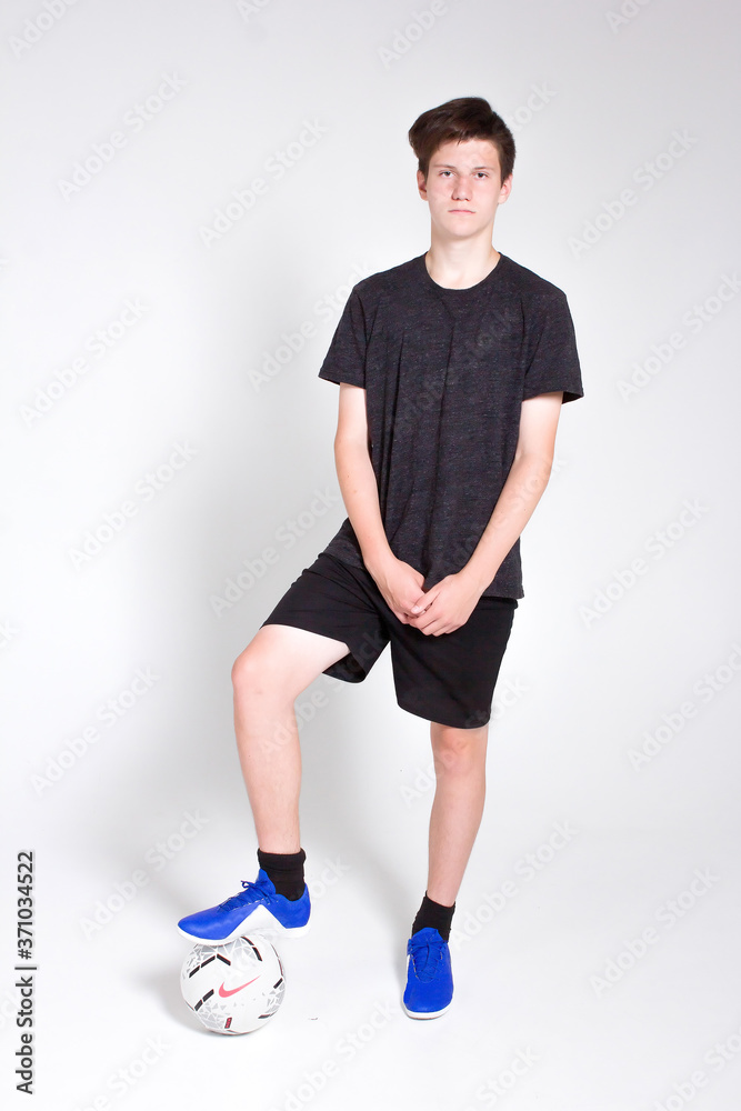 A young man in a black sports t-shirt and shorts, training and playing with a soccer ball.