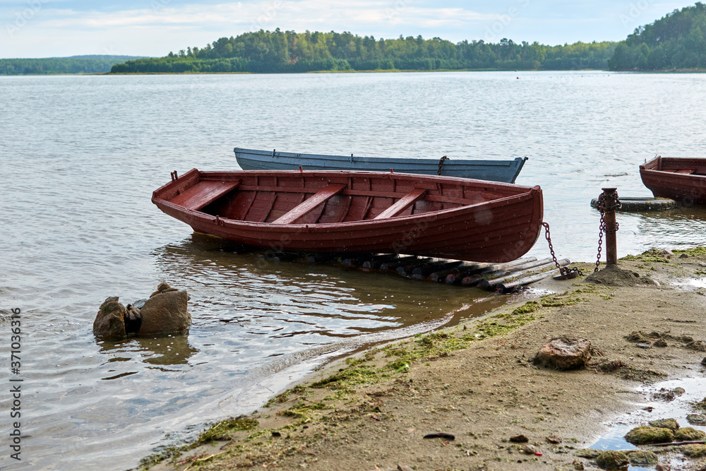 Old wooden boats lie on the shore of the lake. Rain on the lake.
