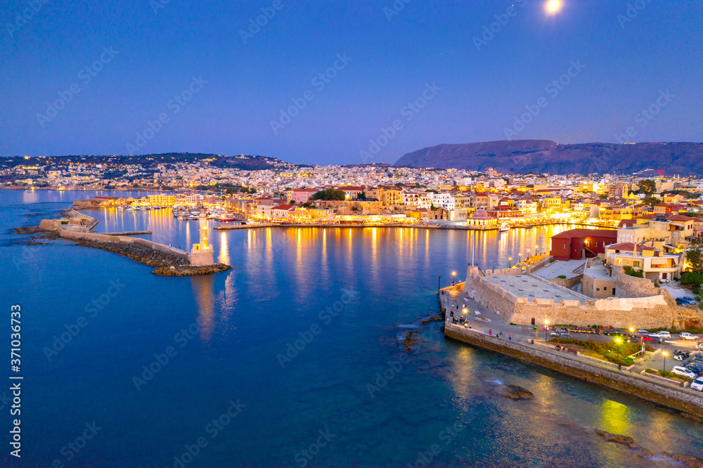 Panorama of the beautiful old harbor of Chania with the amazing lighthouse, mosque, venetian shipyards, at sunset, Crete, Greece.