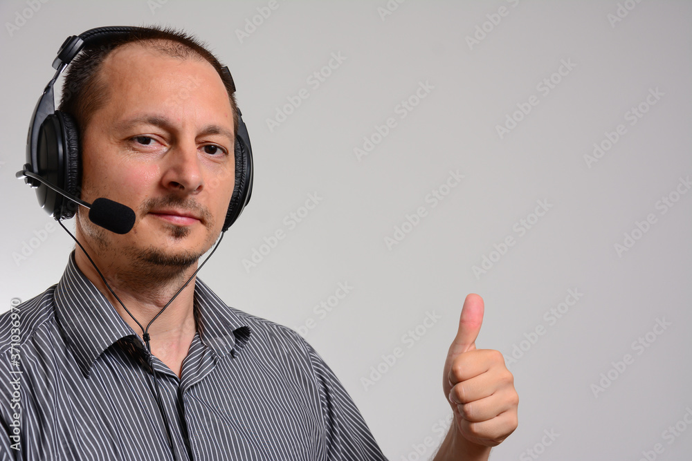 Portrait of handsome mid adult man in work in call-center with headphones and smiling. Male standing over isolated white background Showing palm hand and doing OK gesture with thumbs up, smiling. Portrait of handsome mid adult man in work in call-center with headphones and smiling. Male standing over isolated white background Showing palm hand and doing OK gesture with thumbs up, smiling.