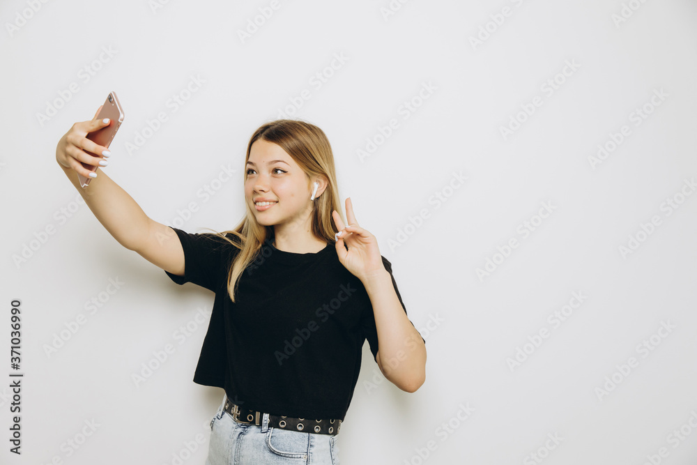 A teenage girl is using a cell phone against grey background A teenage girl is using a cell phone against grey background