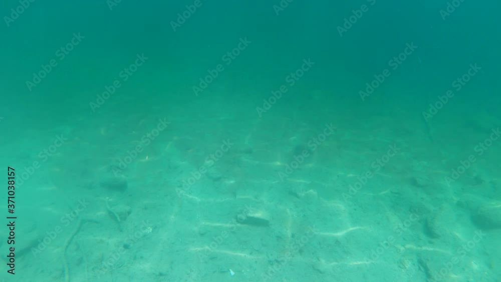 First person view, point of view scuba diving in pristine lake to the bottom. Green colored water. Slow motion deep underwater diving