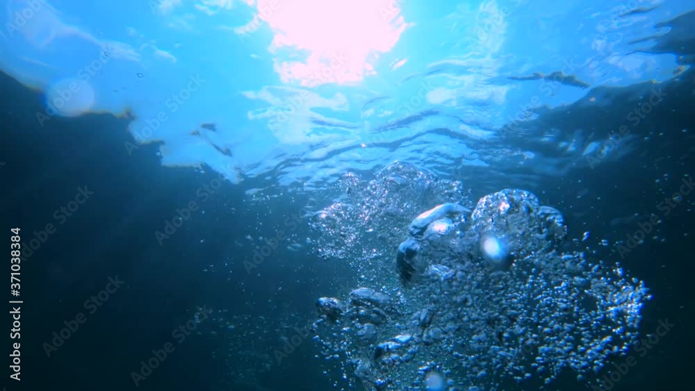 Underwater view of air bubbles floating from seabed to the water surface. Slow motion scuba diver releasing air during the dive. Looking up towards the sun. Drowning concept. First person POV