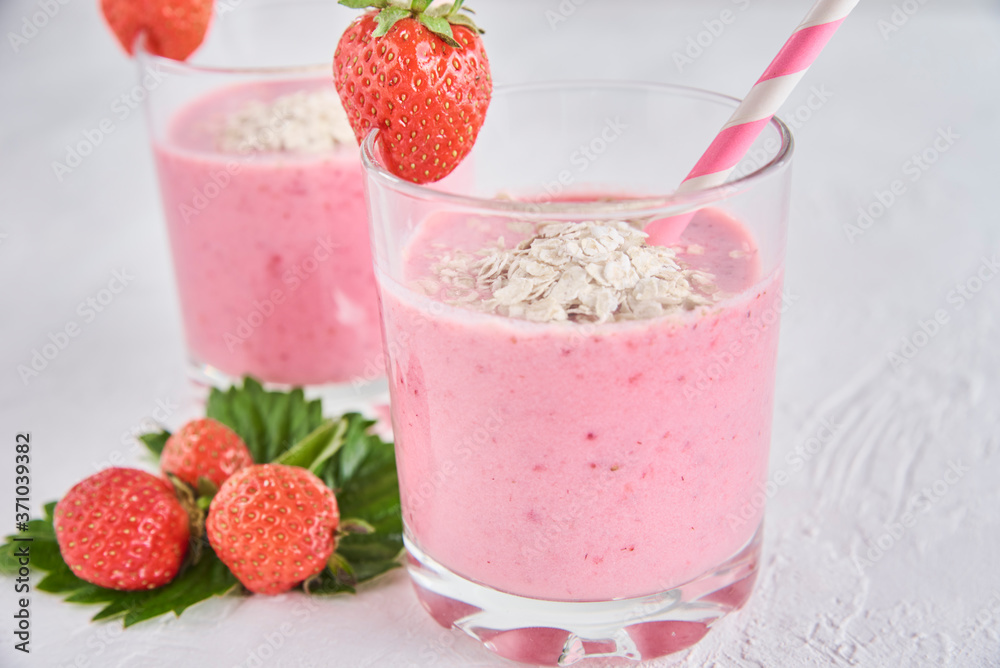 Strawberry milk shake in glass with straw and fresh berries on a white background Strawberry milk shake in glass with straw and fresh berries on a white background