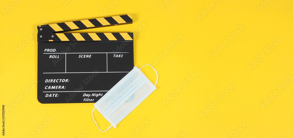 Naklejka premium clapper board or movie slate and face mask on yellow background.
