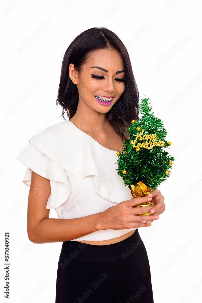 Studio shot of young beautiful Asian woman holding Happy New Year tree isolated against white background Studio shot of young beautiful Asian woman holding Happy New Year tree isolated against white background