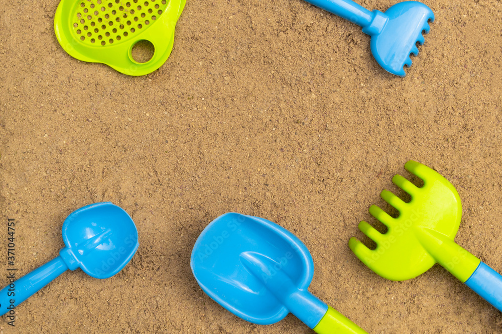 Sandbox. Summer concept. Children's sand toys outdoors. Background with colored shovel, rake, sieve and bucket. Sandbox. Summer concept. Children's sand toys outdoors. Background with colored shovel, rake, sieve and bucket.
