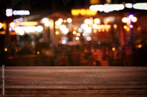 background Image of wooden table in front of abstract blurred restaurant lights © tomertu