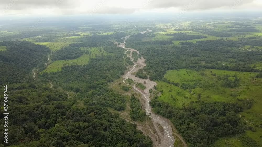 Aerial drone view of a shallow rainforest river surrounded by green meadows full of trees Aerial drone view of a shallow rainforest river surrounded by green meadows full of trees