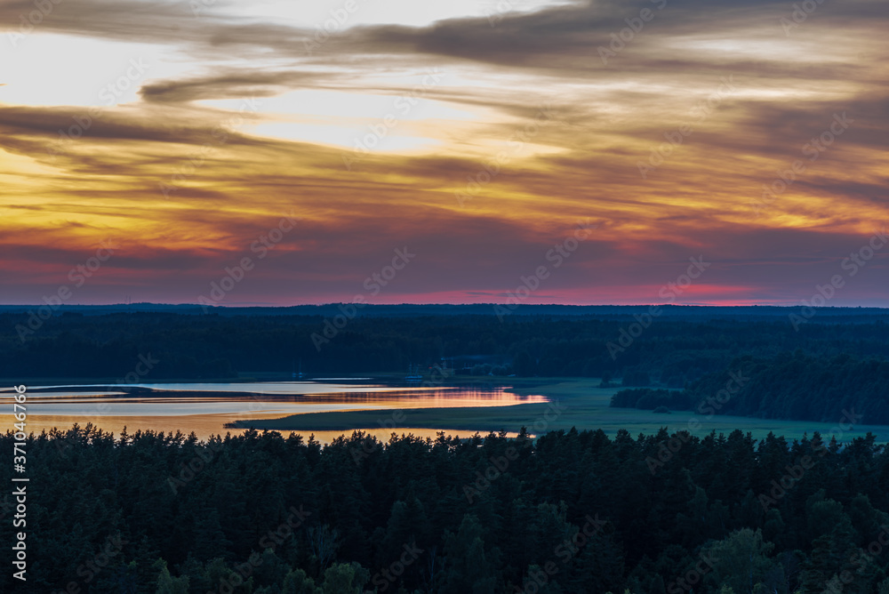 a lake surrounded by forest expanses after sunset
