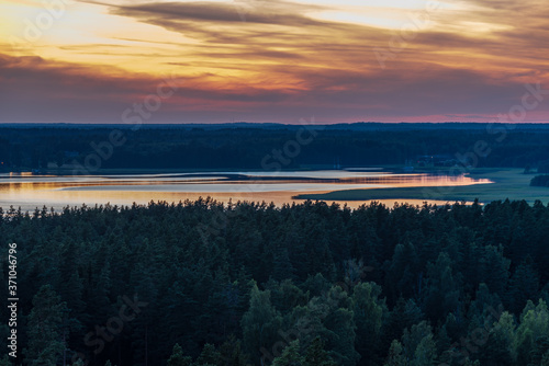 a lake surrounded by forest expanses after sunset