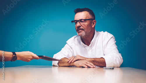 Cropped image of woman's hand showing feedback from followers of website to male skilled CEO waiting for online report using modern touchpad and wireless internet connection in coworking office