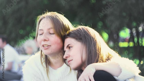 Lesbian couple relax in park in sunny day. Media. Beautiful couple of young lesbians enjoy sunny day in green park. Topic of homosexuality and lesbian relationships. Concept of LGBT