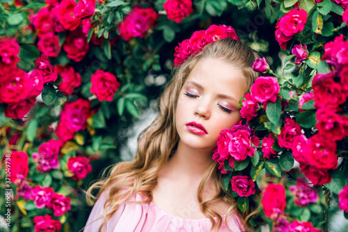 portrait of a young girl with closed eyes against a background of pink roses