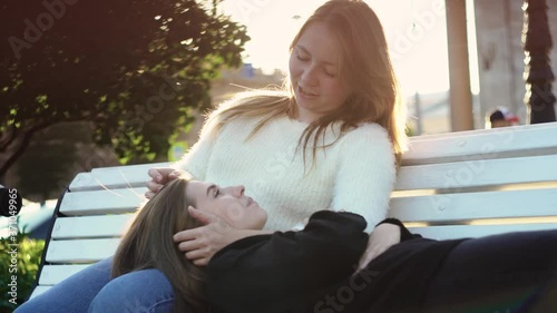 Lesbian couple relax in park in sunny day. Media. Beautiful couple of young lesbians enjoy sunny day in green park. Topic of homosexuality and lesbian relationships. Concept of LGBT