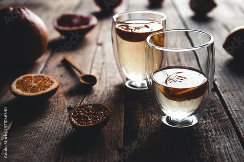 Citrus tea in a transparent teapot and a glass, healthy drink on a wooden background. photo