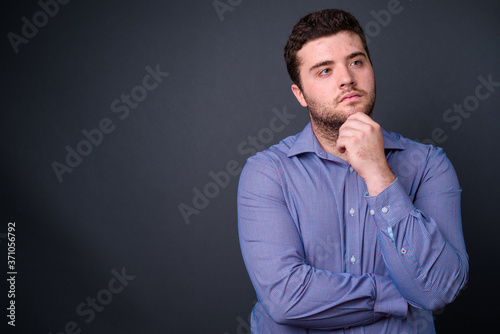 Portrait of young handsome overweight bearded businessman