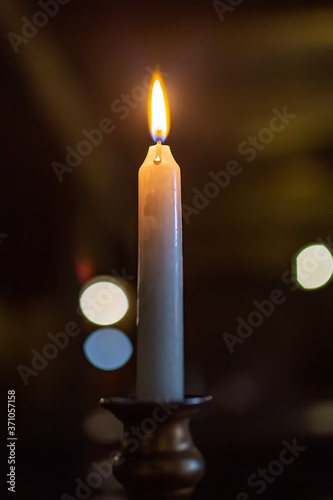 Burning candle on a dark background in an antique candlestick. light.