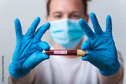 A bacteriologist is holding a blood sample to be tested for COVID-19 photo