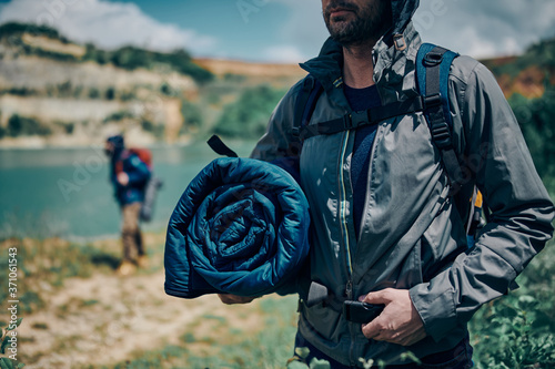 Young attractive man on a camping trip holding sleeping bag.