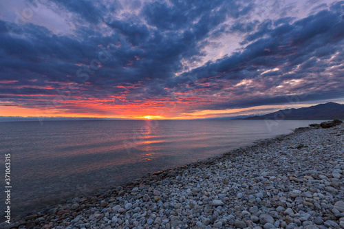 Sunrise and cloudscape at the pebble beach in Issyk Kul Lake  Kyrgyzstan.
