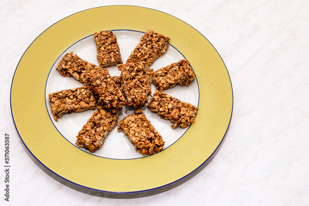Homemade oat and peanut protein bars on a yellow serving plate, the image has some room for text. Homemade oat and peanut protein bars on a yellow serving plate, the image has some room for text.