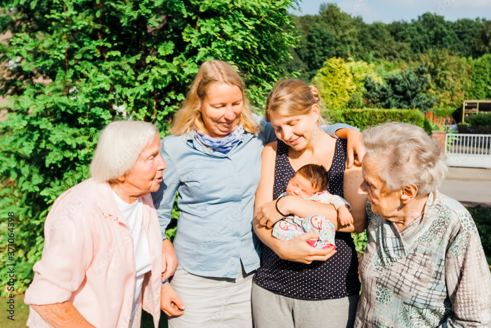 Women of happy multi-generational family with newborn girl outdoors