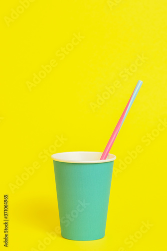 Paper cup with tube on yellow background. Text space