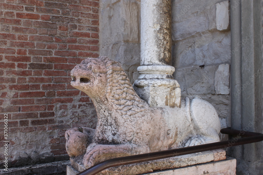 a stone sphinx supports a column at the entrance to a Catholic cathedral