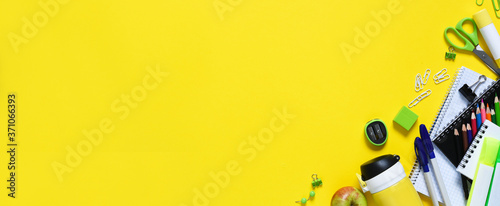 Back to school. School supplies and an apple on a yellow background. Layout of school accessories.Distance learning.