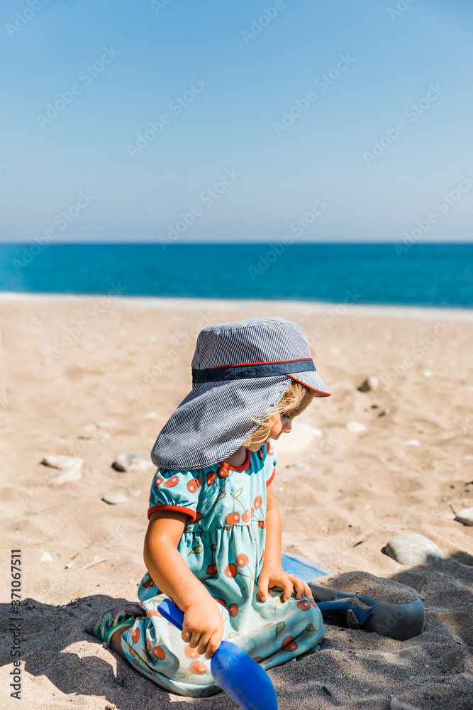 Toddler girl playing with sand on beach Toddler girl playing with sand on beach