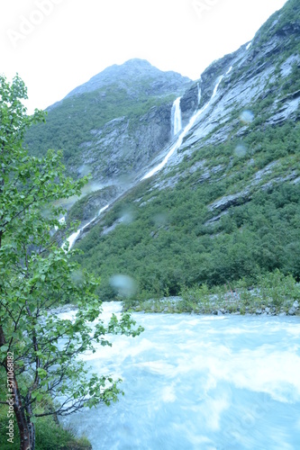 Tall Waterfall in Norway with River and Mountains