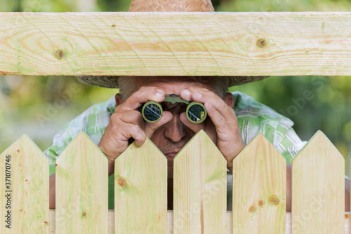фотографія Curious neighbor stands behind a fence and watches