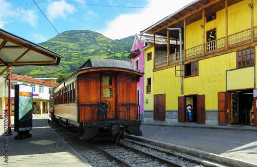 Tourist railway in Alausi, small city in Chimborazo province, to Nariz del Diablo or Devil's Nose. Railroad car parked in front of colorful buildings at train station. Ecuador