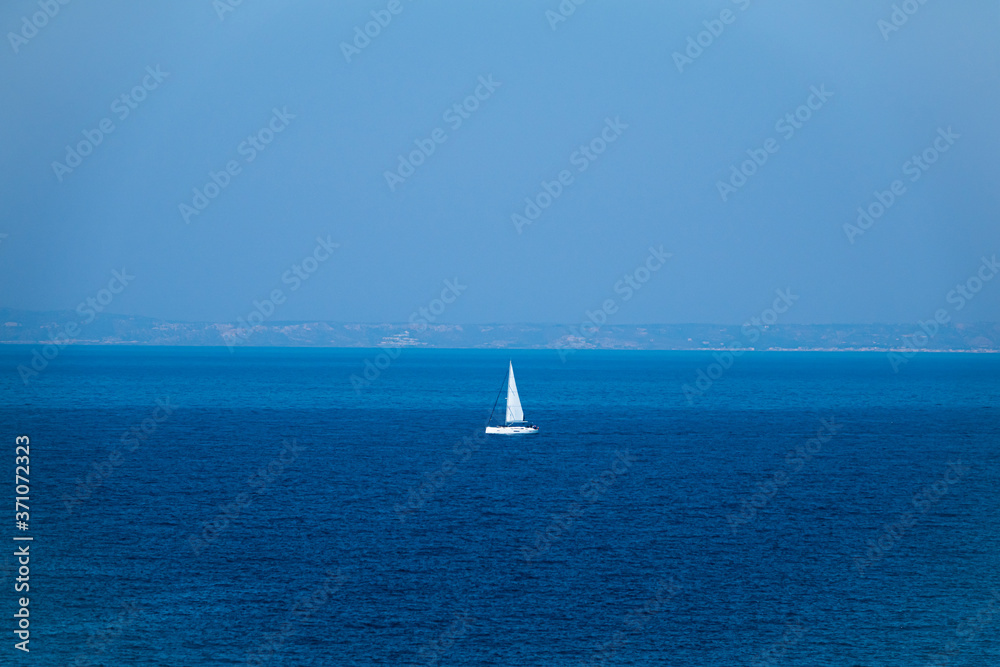 luxury big sailing boat at the horizon on open sea.