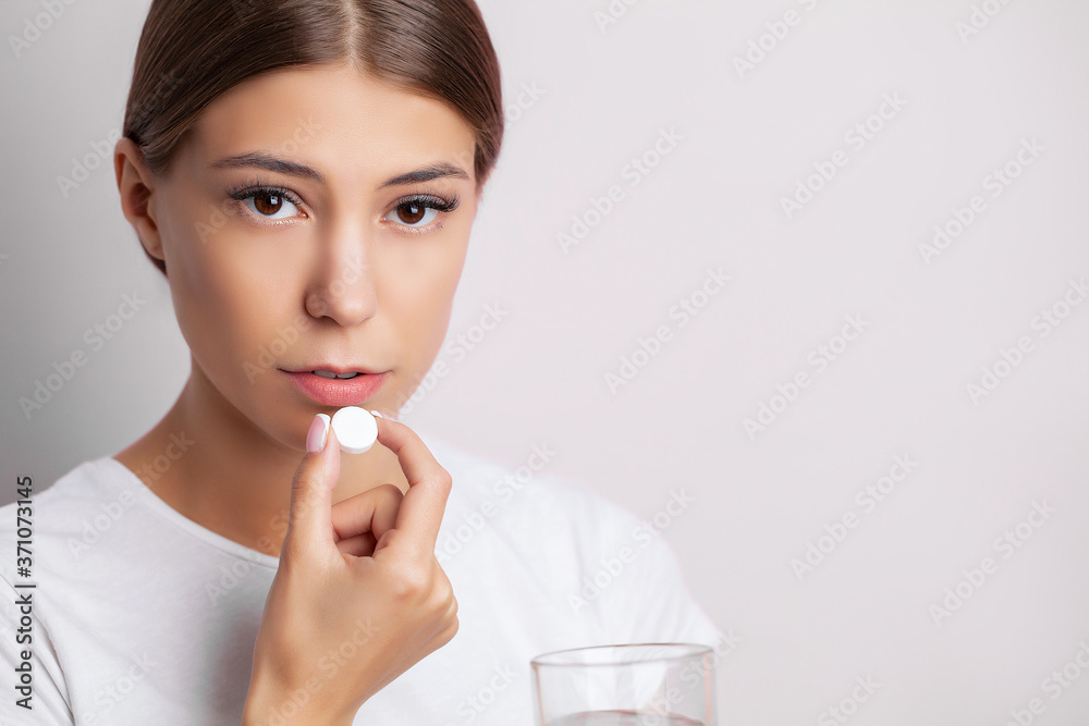 Young woman taking a pill for a headache Young woman taking a pill for a headache