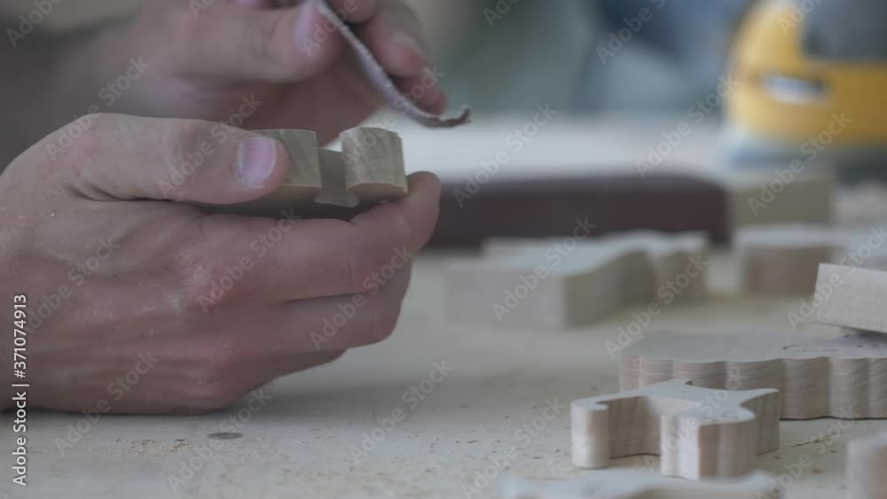 A carpenter polishes eco-friendly wooden toys with sandpaper in his carpentry workshop. A carpenter polishes eco-friendly wooden toys with sandpaper in his carpentry workshop.