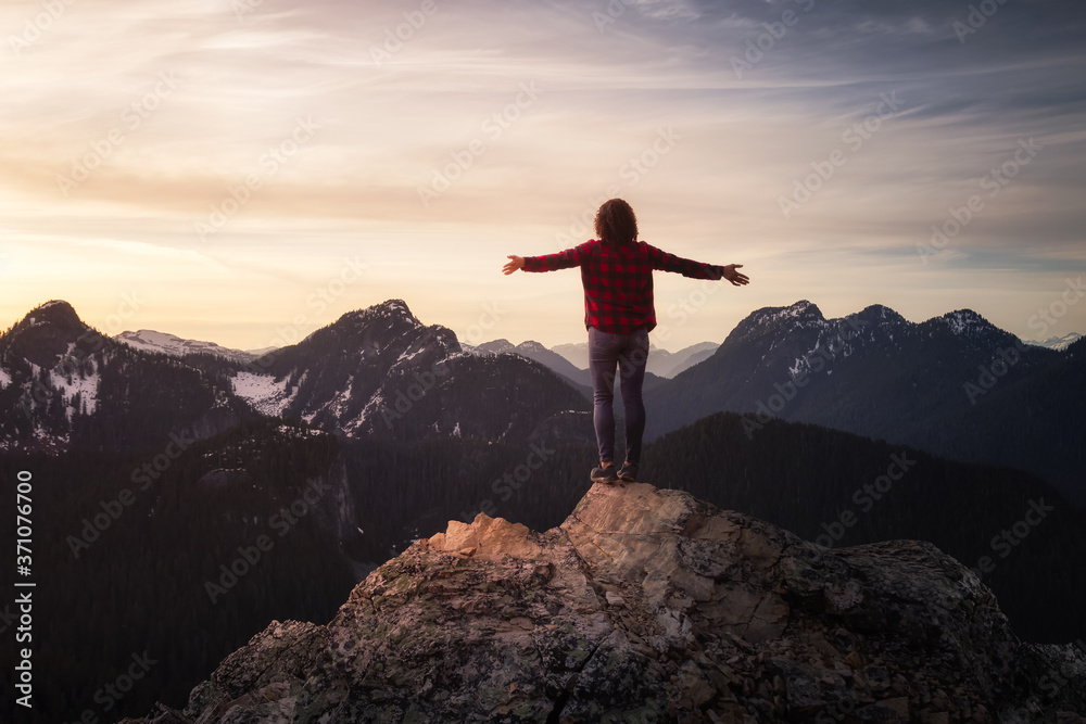 Fantasy Adventure Composite with a Girl on top of a Rock Cliff with Beautiful Nature in Background during Sunset or Sunrise. Landscape from British Columbia, Canada. Concept: Hike, Freedom, Journey
