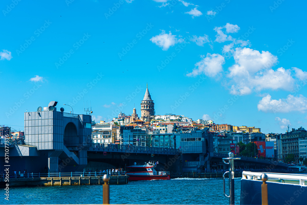 Naklejka premium Galata Tower and Galata Bridge with lots of fish restaurant at sunny day. Scene on Golden Horn Eminonu which is famous tourist area Istanbul, Turkey, June 2020 Karakoy / Istanbul