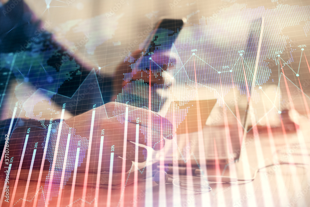 Double exposure of man's hands holding and using a phone and financial graph drawing. Analysis concept.