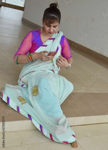 An indian housewife in saree browsing her mobile phone.