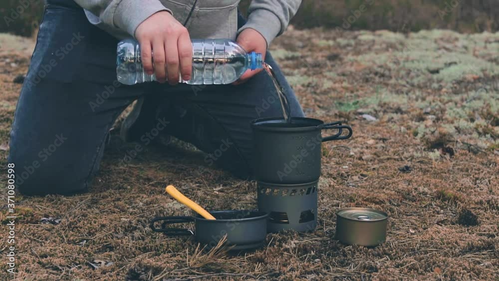 Man in a Hike is Cooking Pasta With Canned Tuna Using a Small Cook Set. Tourist in a Hike is Preparing for the Dinner in Evening. Static Close-Up Shot