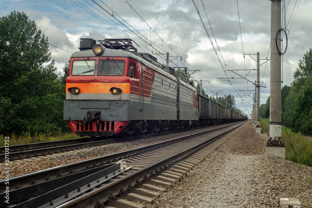 Electric freight train rides on the railway and carries wagons with cargo