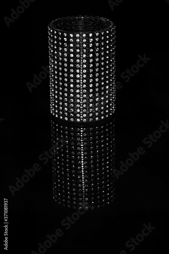 long black women wrist band with diamonds on a black shiny surface. 