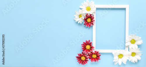 Mockup square white frame with white and red flowers on blue background. View top. Messege or invitation card mock-up concept. flower layut. copy space for text. Banner photo