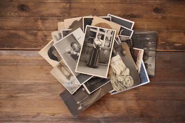 old vintage monochrome photographs in sepia color are scattered on a wooden table, the concept of genealogy, the memory of ancestors, family ties, memories of childhood