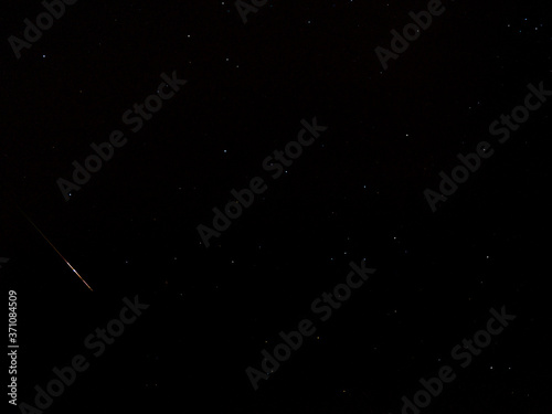 Perseid meteor in the black night sky with stars