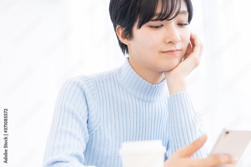 部屋でスマホを見る女性 部屋でスマホを見る女性