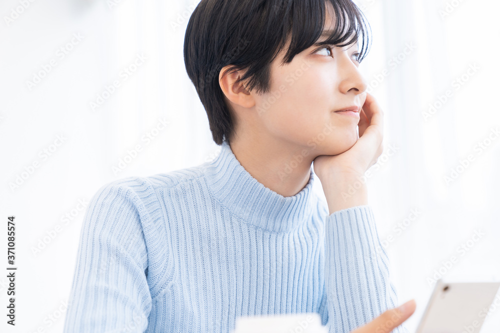 部屋でスマホを見る女性 部屋でスマホを見る女性